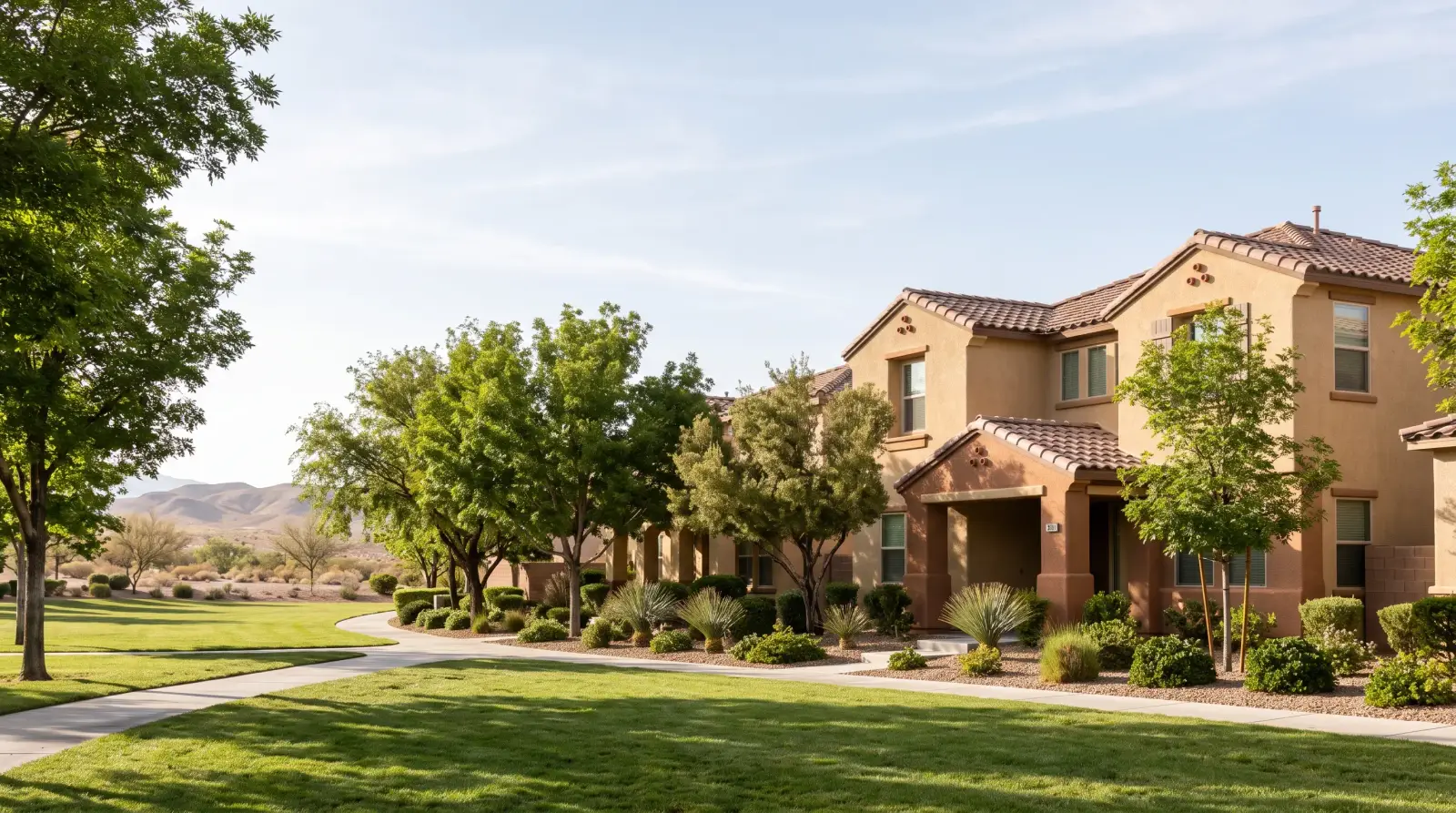 Tile-roofed homes beside a green lawn and mature trees in Green Valley, Nevada